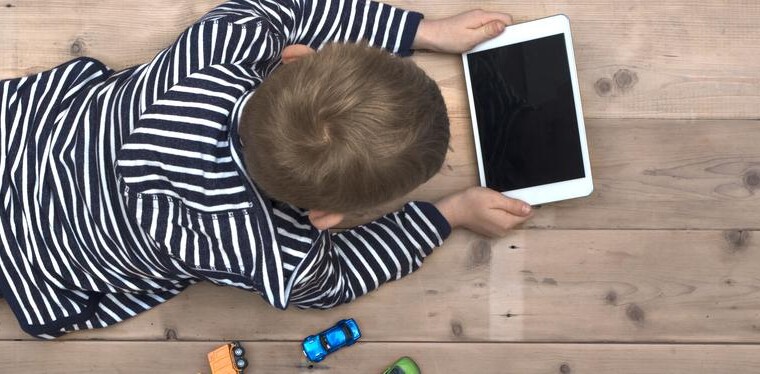 enfant avec un écran dans les mains qui délaisse ses jouets