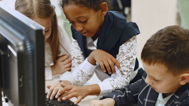 es élèves de CM2 rédigeant à tour de rôle sur les ordinateurs de la classe
